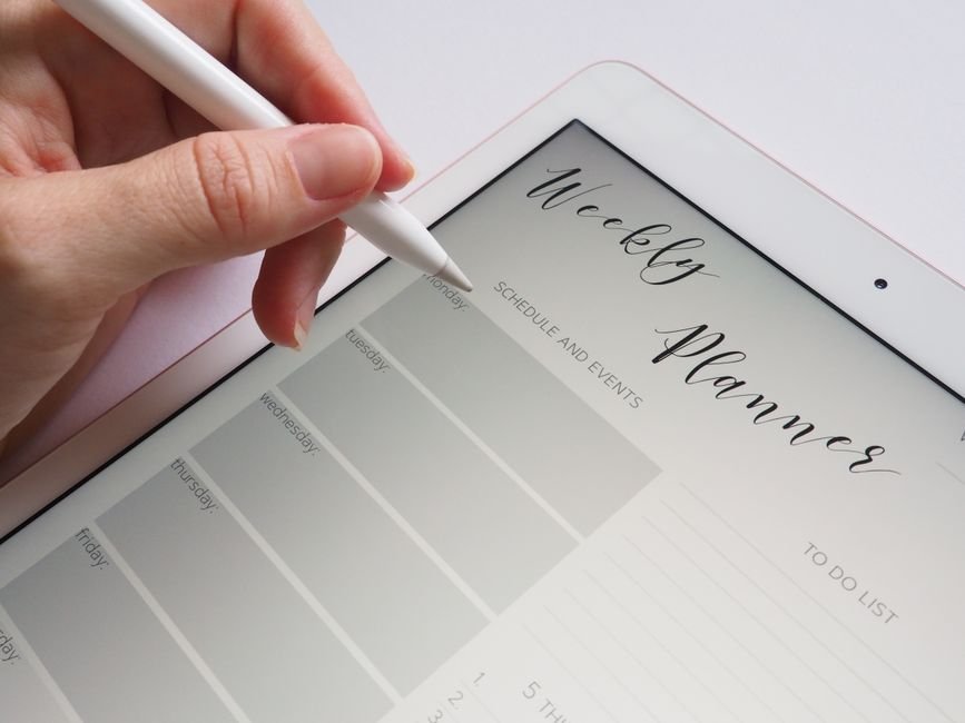 A hand using a stylus on a digital weekly planner, relevant to digital planners' value.