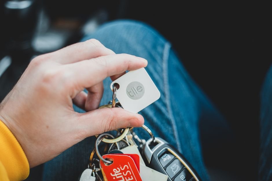A person holding a Bluetooth key finder attached to a keychain, illustrating the article on key finders.