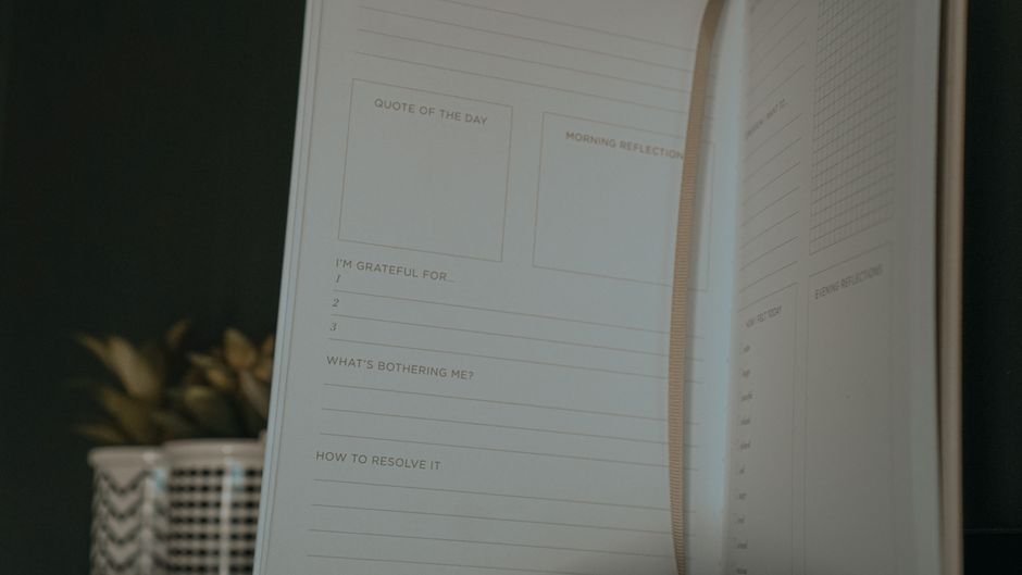 A habit tracking journal open to pages with reflection prompts and gratitude sections, related to habit tracking.