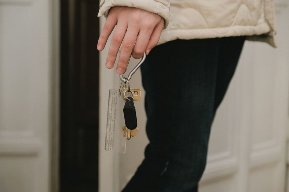 A person holding a set of keys with a Bluetooth key finder attached, relevant to key finders for Android.