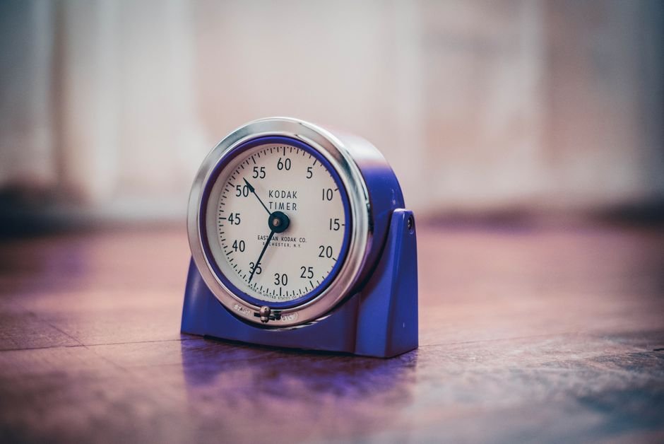 A vintage kitchen timer on a wooden surface, illustrating how to set a timer.