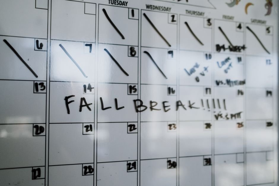 A whiteboard monthly planner displaying dates and notes, including 'Fall Break' highlighted.