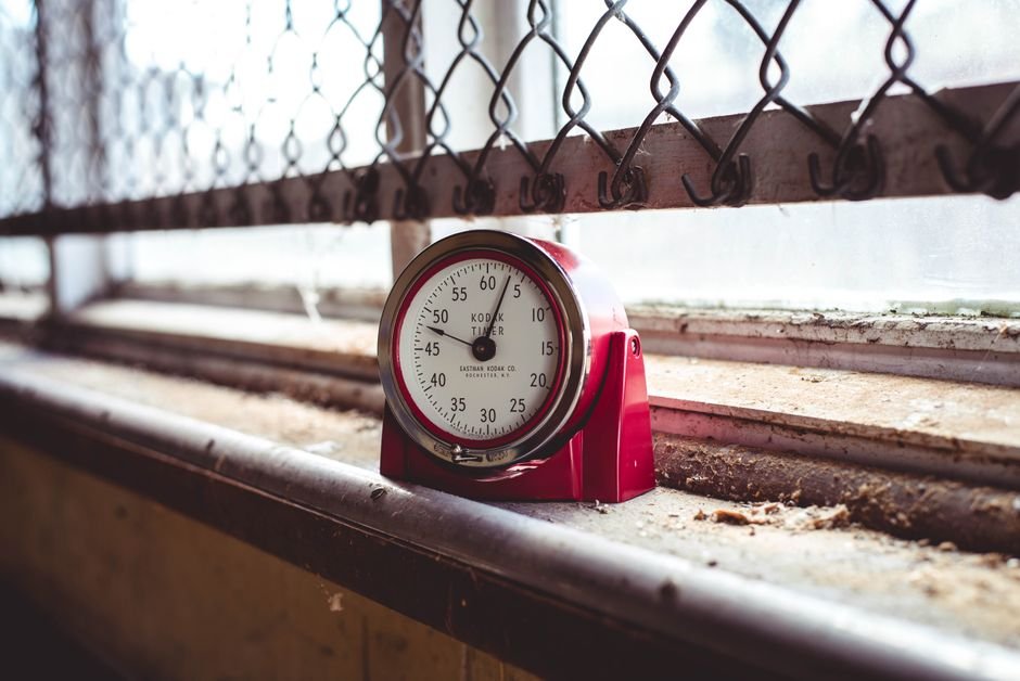 An analog timer sits on a windowsill, illustrating the comparison of analog and digital timers.