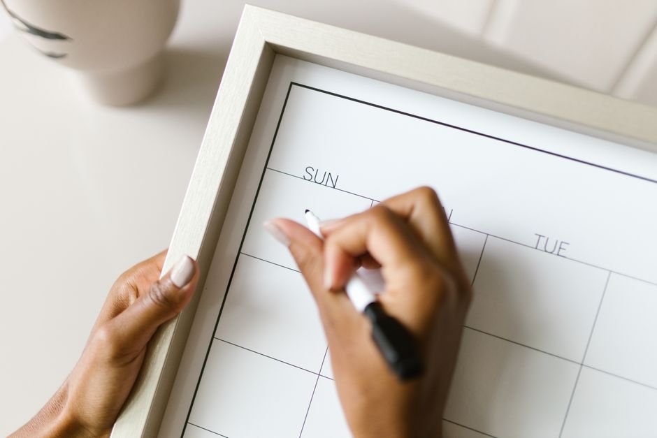 A person writing on an erasable wall calendar, illustrating organization tools.