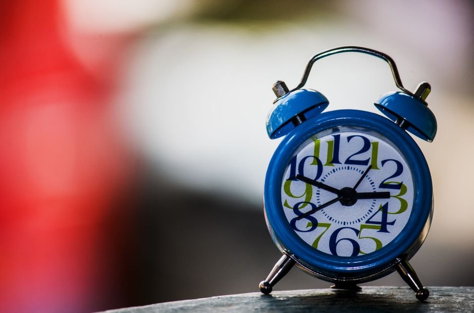 A blue alarm clock with a white face and colorful numbers, illustrating how to change an alarm clock battery.
